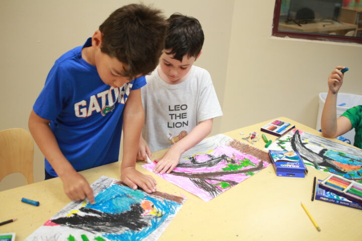 Two boys are working on art at a table.
