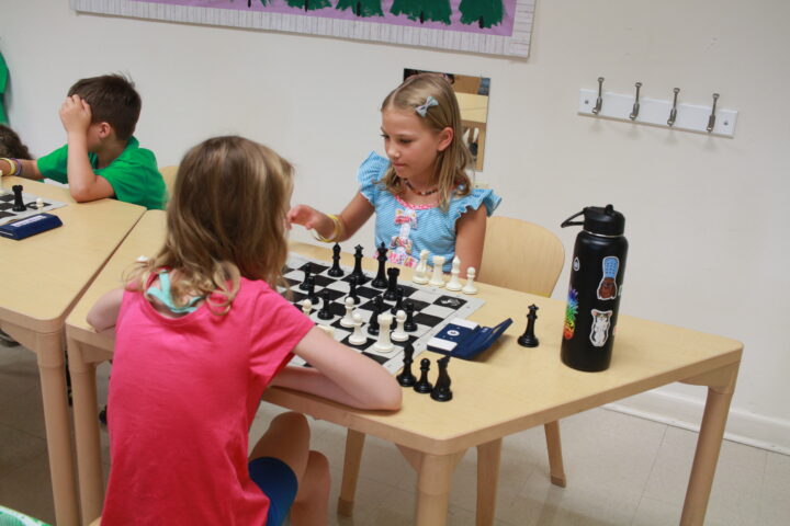 Children playing chess in a classroom.