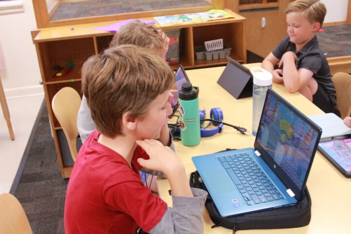 A group of children using laptops in a classroom.