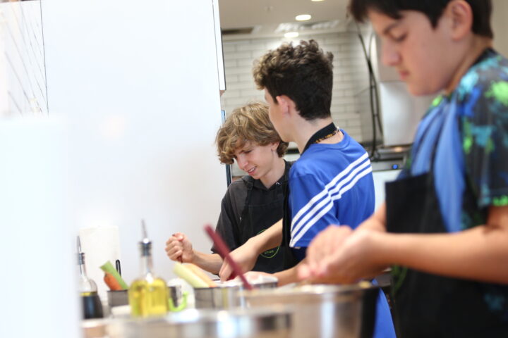 A group of boys are preparing food in a kitchen.
