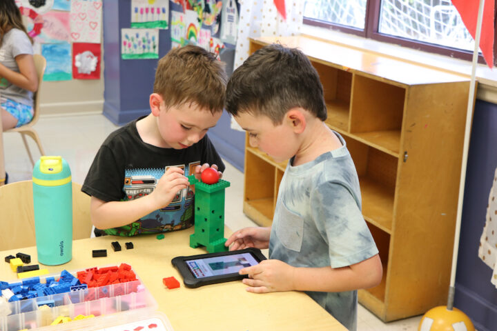 Two young boys playing with legos in a classroom.
