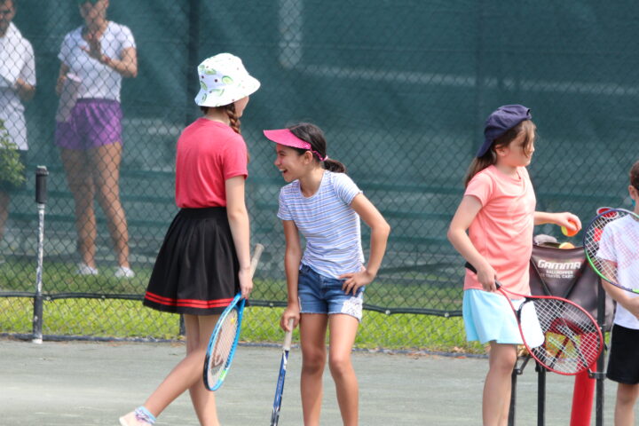 A group of children on a tennis court.