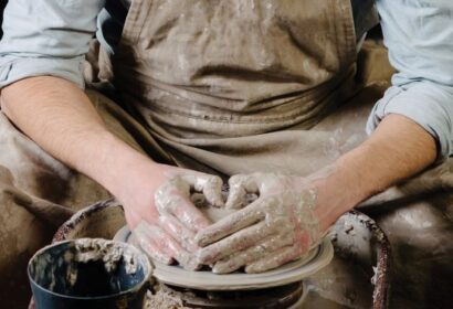 A man in an apron is working on a potter's wheel.
