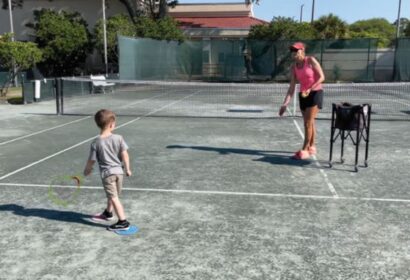A woman and a child playing tennis on a tennis court.