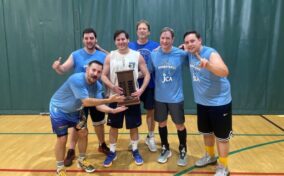 A group of men posing with a trophy in a gym.