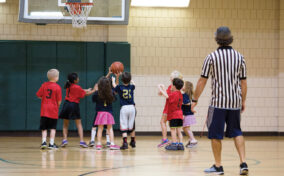 A group of children playing basketball in a gym.