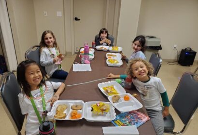 A group of children sitting at a table with food.