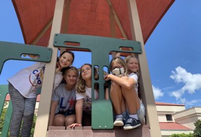 A group of girls sitting on top of a playground structure.