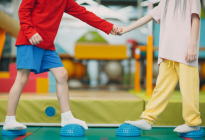 Two children are holding hands in an indoor gym.