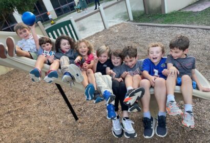 A group of children sitting on a playground slide.