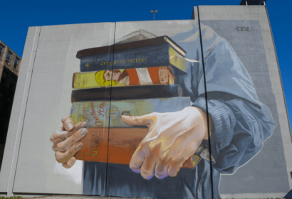 A mural of a hand holding books on a building.