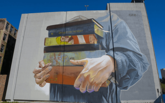 A mural of a hand holding books on a building.