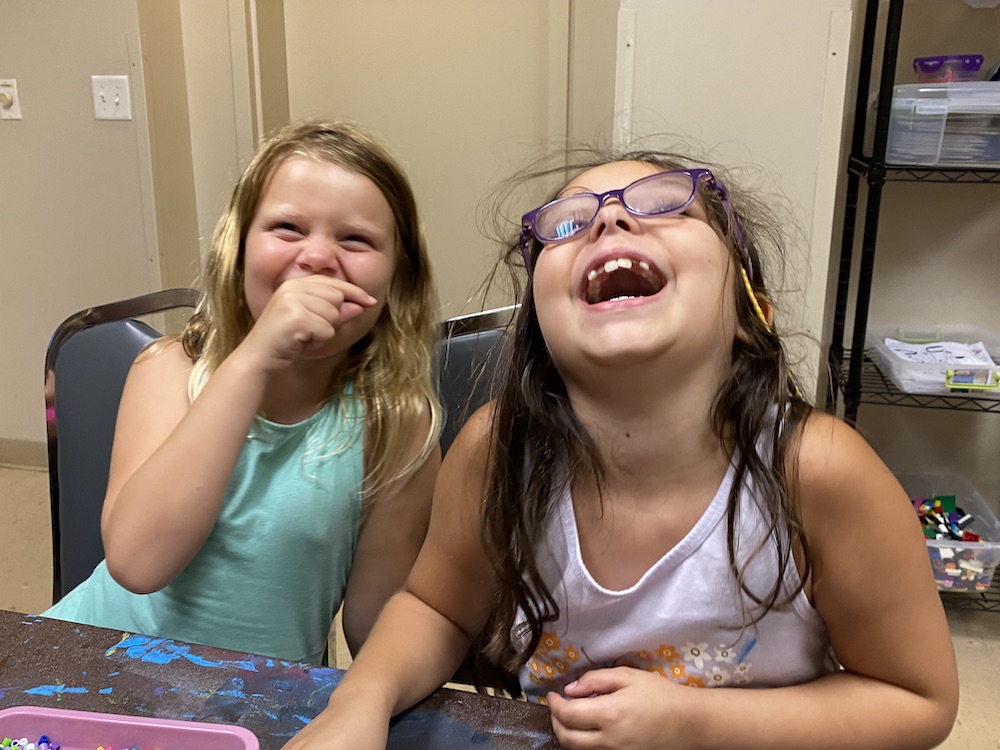 Two girls laughing at a table.