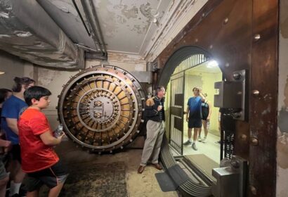 A group of people standing in front of a large bank vault.