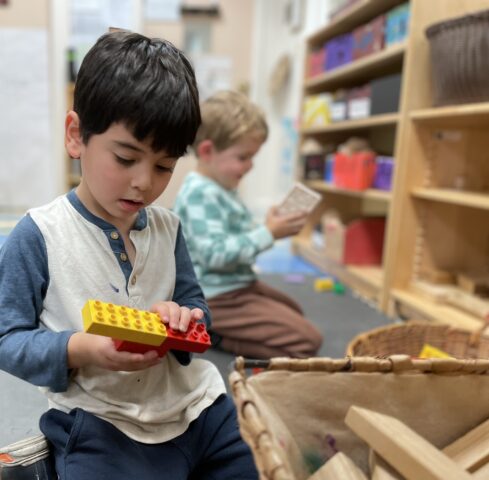 A young boy playing with legos in a classroom.