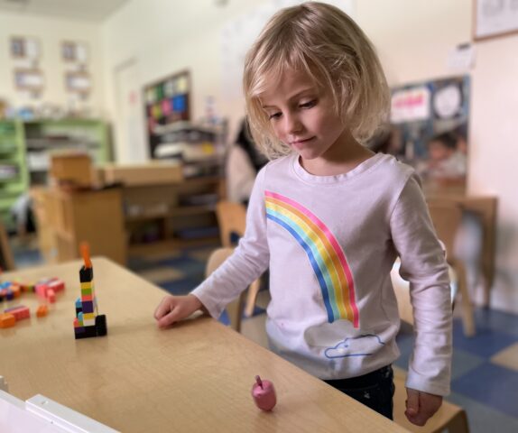 A little girl playing with blocks in a classroom.