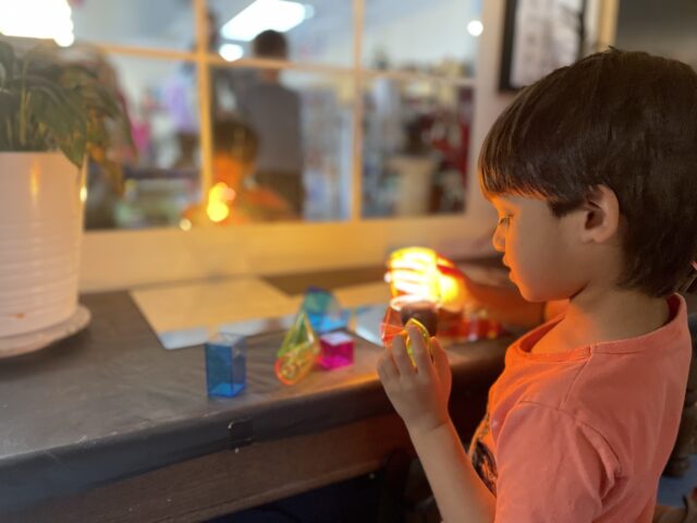 A young boy playing with a toy in front of a mirror.