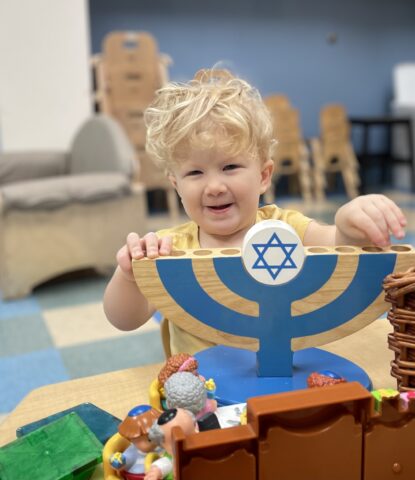 A toddler playing with a hanukkah menorah.