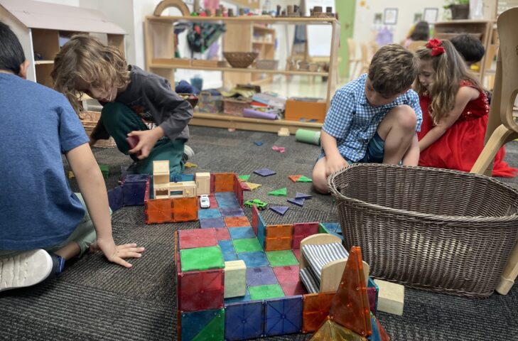 A group of children playing with blocks in a classroom.