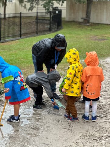 A group of children playing in a puddle.