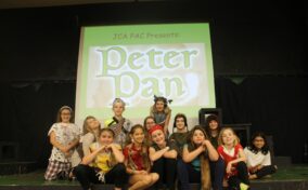 A group of children from Youth Theatre smiling from a Peter Plan play