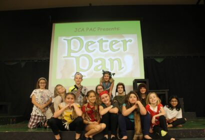 A group of children from Youth Theatre smiling from a Peter Plan play