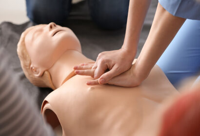 Instructor demonstrating CPR on mannequin at first aid training course.
