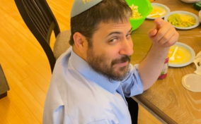 Rabbi Shmuli Novack smiling and pointing during lunch.