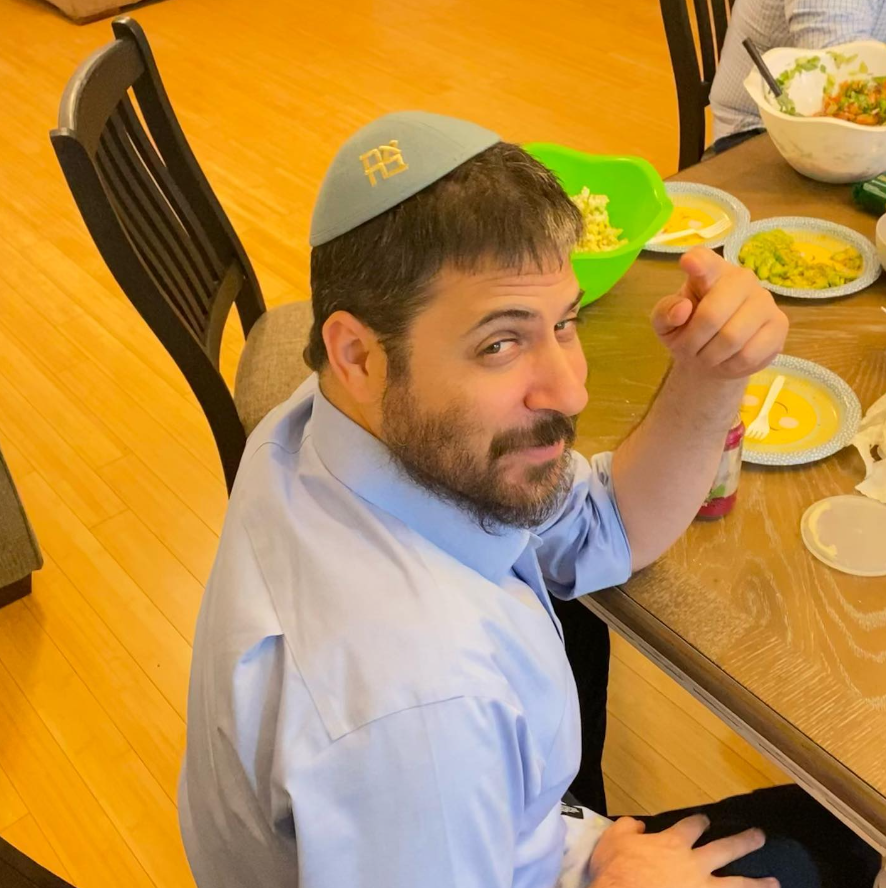 Rabbi Shmuli Novack smiling and pointing during lunch.