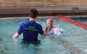 A girl swimming with swim instructor during Sensory Swim Lessons in the indoor pool.
