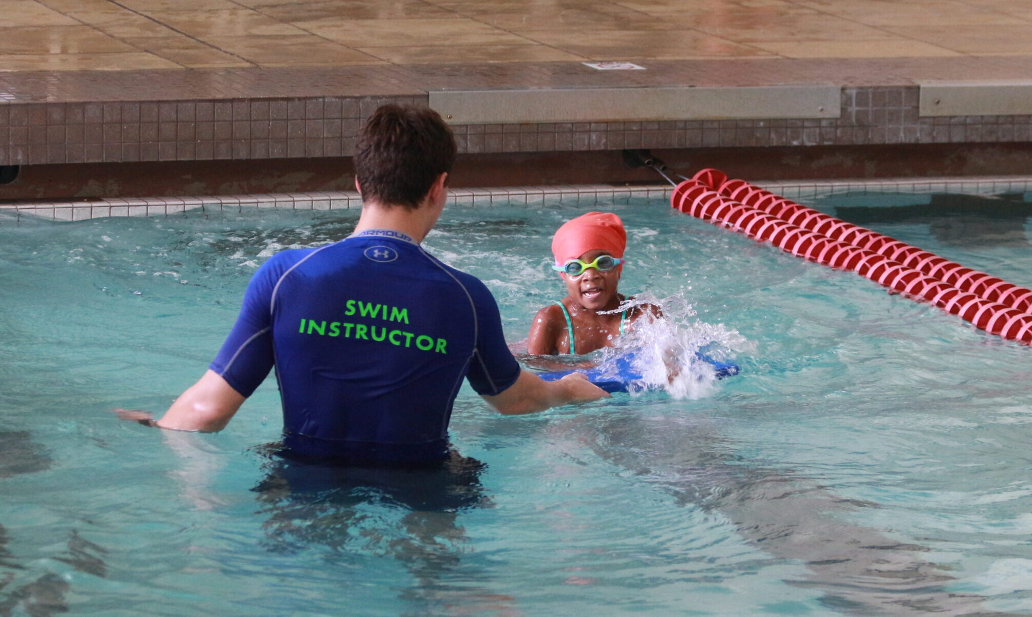 A girl swimming with swim instructor during Sensory Swim Lessons in the indoor pool.