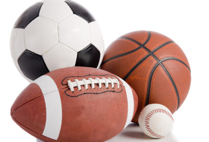 Four sports balls are shown: a soccer ball, a basketball, an American football, and a baseball, all placed on a white background.