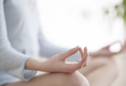 Person sitting cross-legged in a meditative posture with their hands resting on their knees, forming a mudra gesture.