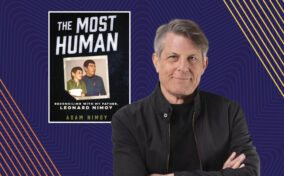 A man in a black jacket stands with folded arms next to a book cover titled "The Most Human" by Adam Nimoy, featuring a photo of Leonard Nimoy. The background has blue and yellow abstract patterns.