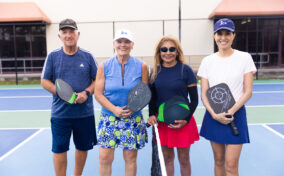 A group of adults smiling on the pickleball courts