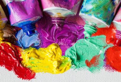 Tubes of paint squeezed out onto a canvas, showing vibrant colors including red, yellow, blue, pink, purple, and green.