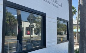 Exterior of "Got Flowers Jax" floral shop with two large windows and palm trees in front.