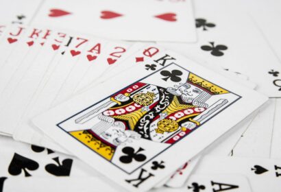 A deck of playing cards scattered on a surface, with the King of Clubs prominently visible in the center.