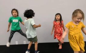 Four children are engaged in playful activity indoors.