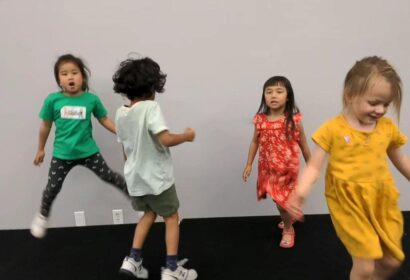 Four children are engaged in playful activity indoors.