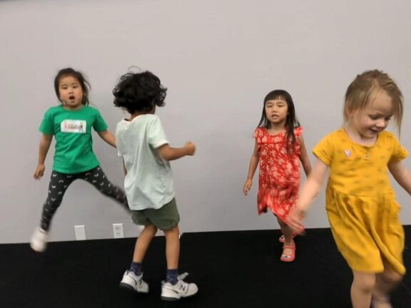 Four children are engaged in playful activity indoors.