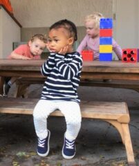 Preschoolers sitting outside on bench together