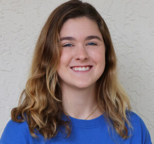 A young woman wearing a blue t - shirt.