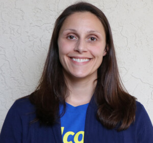 A smiling woman wearing a blue t - shirt.