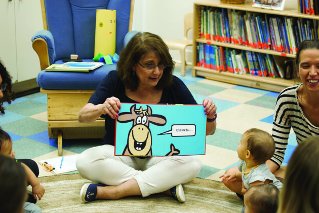 A woman reading a book to a group of children.