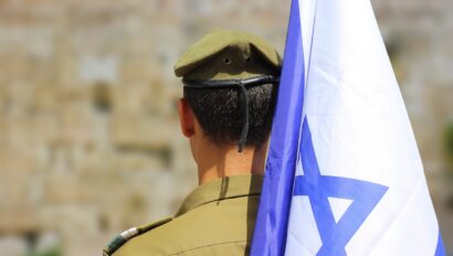 An israeli soldier holding an israeli flag.