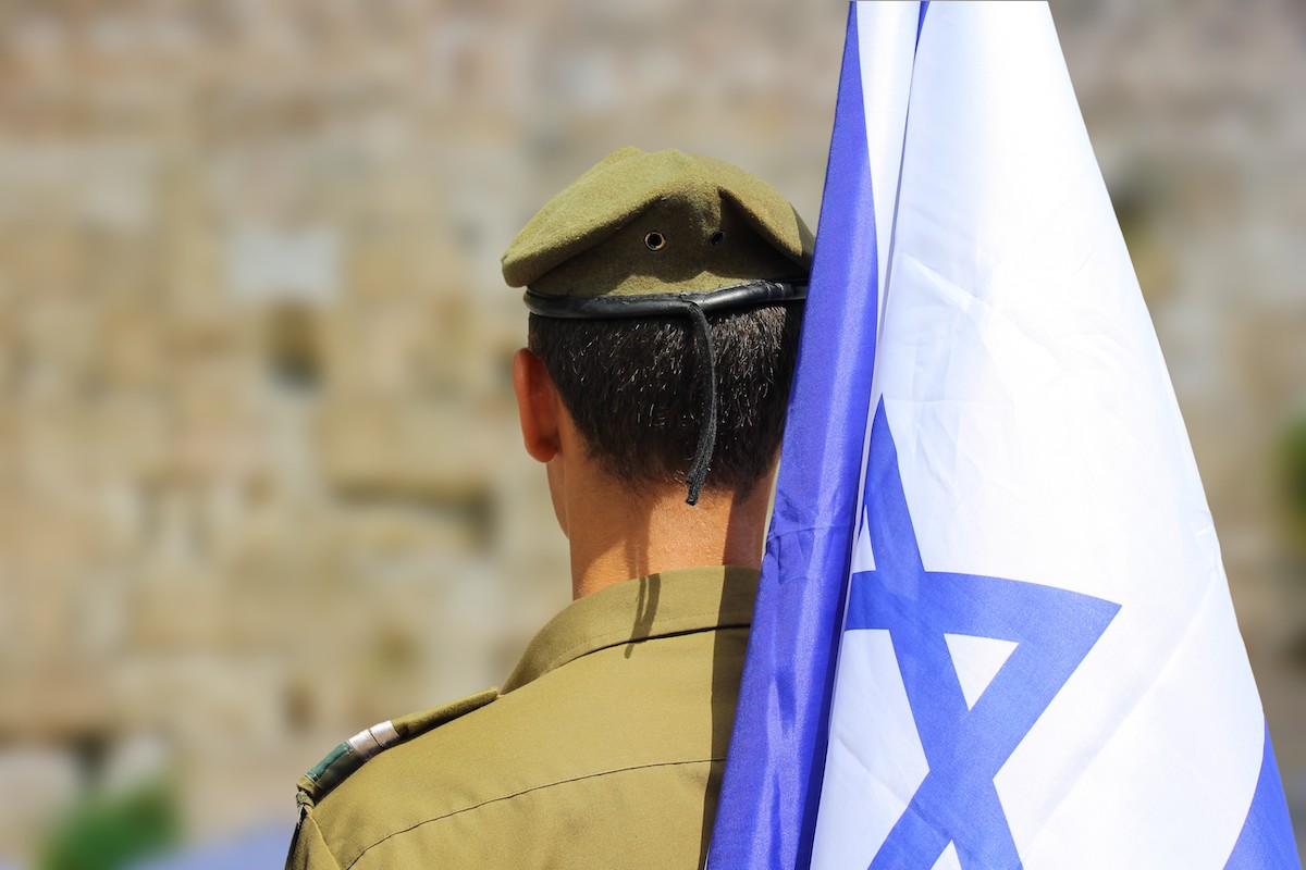 An Israeli soldier holding an Israeli flag. Yom Ha’Zikaron, Israel’s Memorial Day to honor fallen soldiers and civilian victims of terrorism, begins at sundown on April 29 and ends at sundown on April 30.