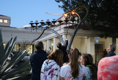 A group of people watching a menorah.