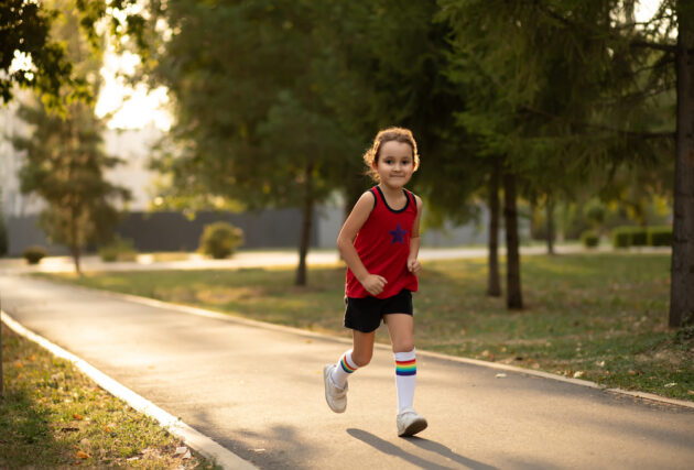 A little girl running on a path in a park.