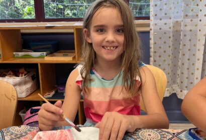 Girl smiling with paintbrush in hand as she paints.